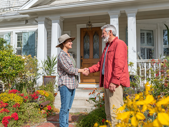a couple shaking hands in front of a house representing Title Insurance